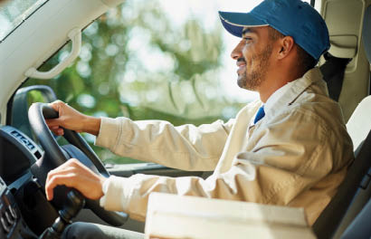 Shot of a happy delivery man driving his van with boxes in the front seat