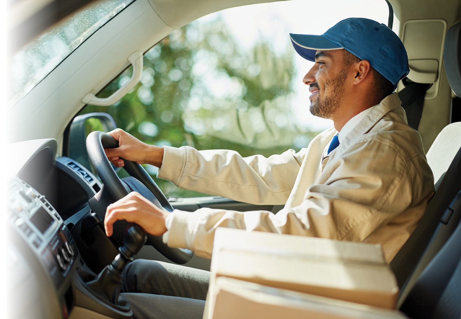 Shot of a happy delivery man driving his van with boxes in the front seat