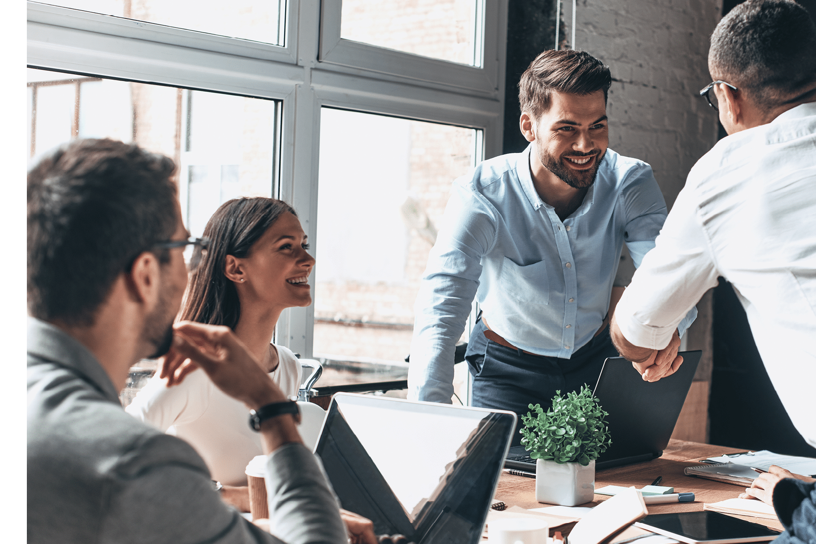 Young modern men in smart casual wear shaking hands and smiling while working in the creative office