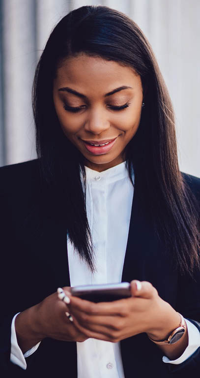 Positive african american businesswoman dressed in formal wear laughing during messaging online on smartphone device via 4G internet Cheerful dark skinned female office worker installing application