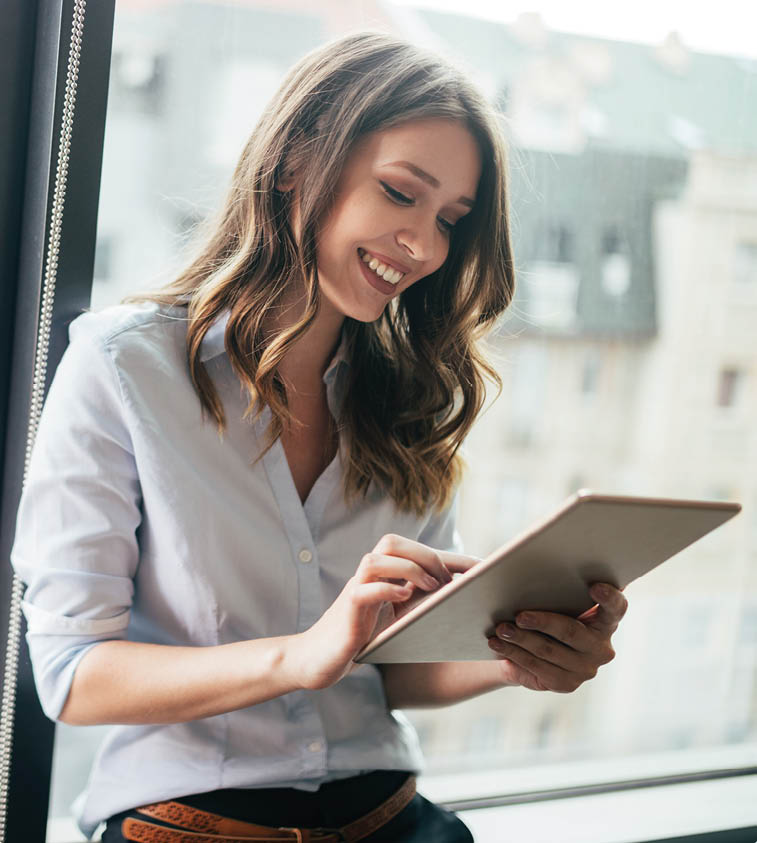 Young businesswoman using a digital tablet while standing in front of windows in office