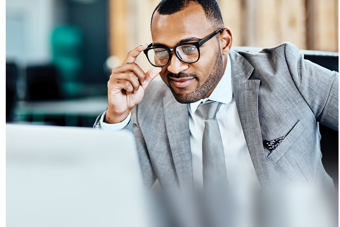 Cropped shot of a handsome young businessman sitting alone in his office and smirking while using his laptop