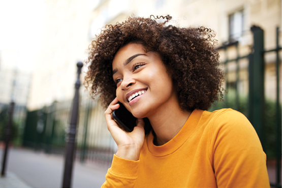 Close up portrait of happy african american young woman talking with cellphone in city