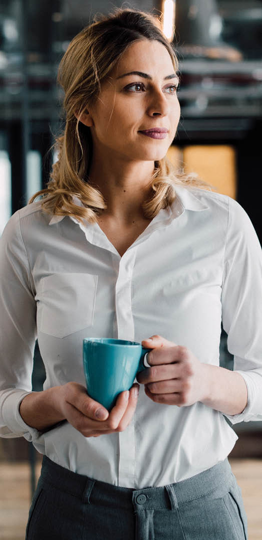 Thoughtful businesswoman looking away with cup of coffee