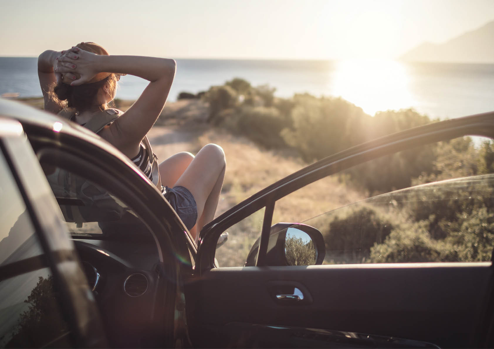Woman relaxing on her car at the road trip