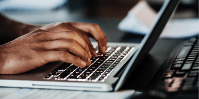 A close up of a man typing on his laptop at the office 